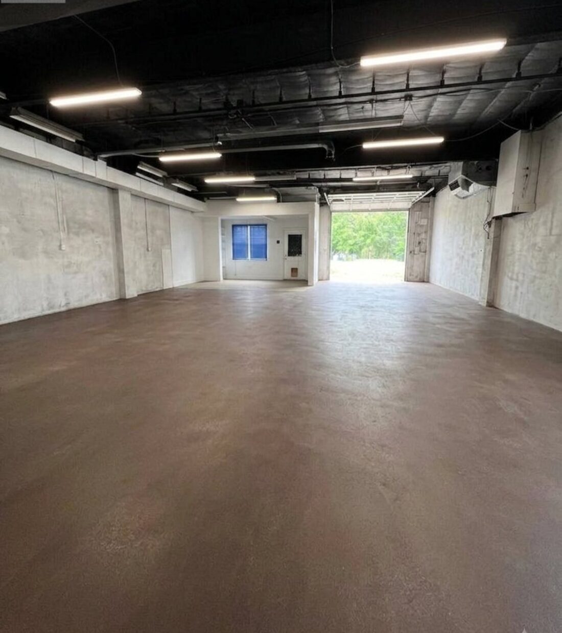 The interior looking toward an open
          garage bay with daylight and trees beyond.